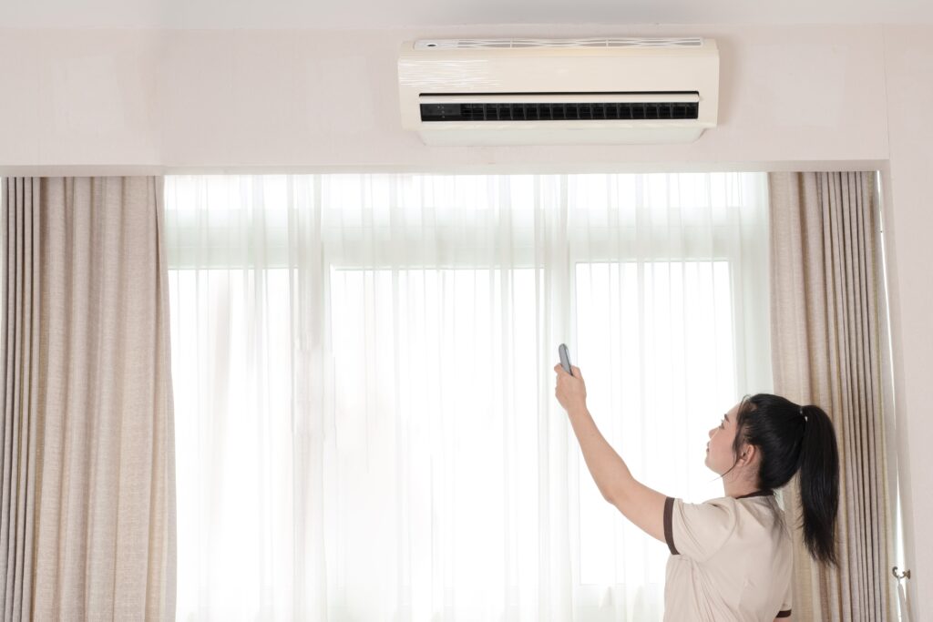 chambermaid in a hotel room She is holding a remote control to be opening the air conditioning unit